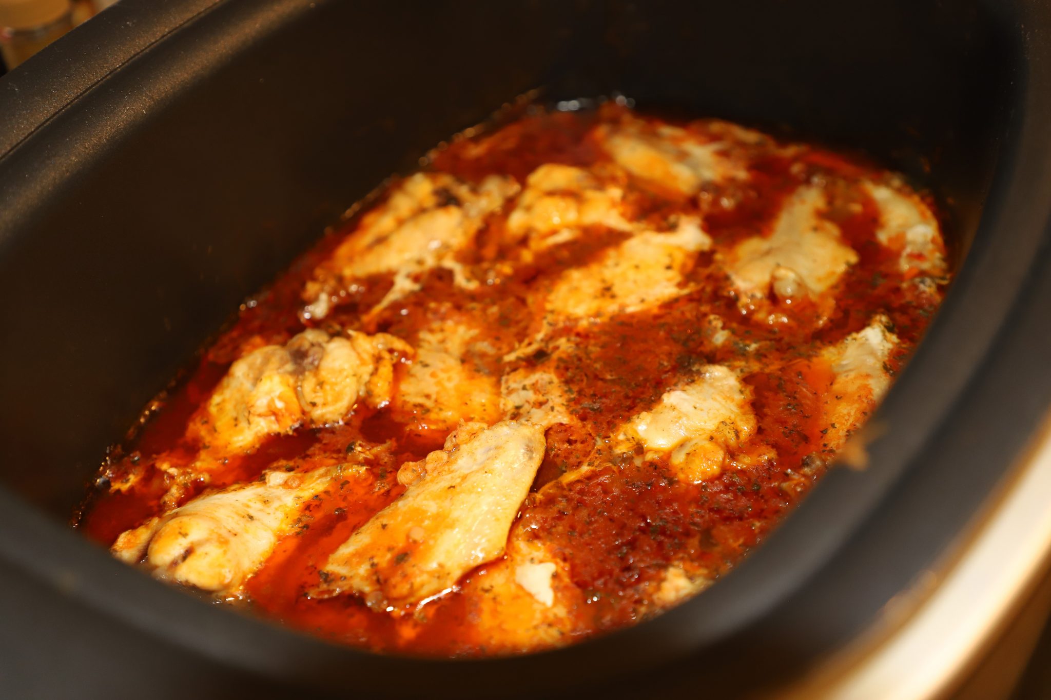 Hot sauce, butter, and seasonings being whisked together in a bowl